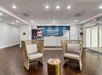 Hotel lobby with two wicker chairs and a small round table in front of a reception desk. The wall behind the desk reads "Welcome to the Sunshine State.