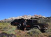 A man standing next to a black Jeep Gladiator with another Jeep behind it on a sunny day in Zion National Park.