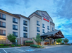 Fairfield Inn & Suites building with five floors, parking spaces, and a wooden entrance canopy under a cloudy sky.