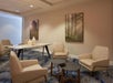 A sitting area with beige geometric chairs, a black coffee table, a long beige table with vases on it, and two pieces of art on the walls.