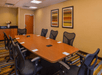 Meeting facility equipped with a long wooden table and black office chairs.