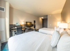 Hotel room with two double beds, a desk, a flat-screen TV, and soft lighting. Neutral color scheme with beige walls and white linens.