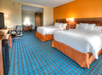 Two queen beds, flat-screen TV, mini-fridge and a work desk inside a guest room.