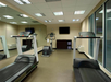 A small gym with two treadmills, an exercise bike, a mirror wall, and a TV. There's a unit with towels on shelves beneath the TV.
