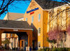 Exterior view of a Residence Inn hotel with a yellow facade, stone accents, and blooming trees in front.