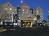 The front exterior and covered entrance and drive way of the Fairfield Inn & Suites Orlando at night with an empty parking lot.