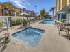 An outdoor swimming pool and hot tub with lounge chairs and tables with umbrellas on the sides on a sunny day at the Fairfield Inn & Suites.