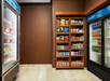 A small convenience store area with shelves of snacks, refrigerated beverages, and sandwiches in a hotel setting.