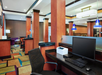 Office space featuring desks with computers, a printer, modern wooden pillars, colorful carpet, and blue pendant lights.