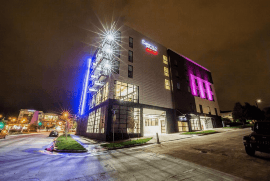 Exterior of the Fairfield Inn & Suites Denver Downtown with blue, pink, and white lights shining bright at night in Denver Colorado.
