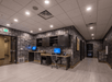 A small business center with two desks, one standing and one sitting, in an open hallway with gray wallpaper at the Fairfield Inn & Suites.