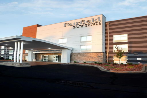 Front view of Fairfield Inn & Suites by Marriott, featuring a modern exterior with a covered entrance, large windows, and a landscaped area.