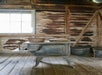 Close up of a dusty old wood stove with an old pot and pan sitting on the top of it and two old pots on the floor to the right.