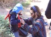 NAVTEC tour guide kneeling down and making sure that a child's life jacket is a proper fit.