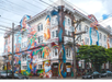 A building with elaborate, colorful murals covering its facade, depicting various human and abstract figures. Power lines crisscross overhead, and a street sign is visible.