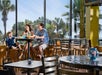Dining area with huge windows overlooking tall palm trees.