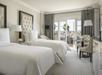 Bright and cozy space featuring two twin beds, a table, and a balcony with views.