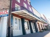 Street view of a row of colorful buildings featuring the French Market Inn with a red and white facade, black railings, and a sign reading "French Market Inn" at the entrance.