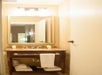 Bathroom with a large mirror, a granite countertop sink, and neatly arranged towels and toiletries on a wooden vanity shelf.