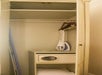 Open wardrobe with an ironing board, iron, hangers, and a safe inside.