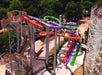 Aerial view of a colorful, multi-lane water slide structure surrounded by trees and adjacent to a wooden roller coaster.