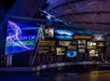 A science-themed exhibit with illuminated displays titled "Power of Science." Various screens and panels present scientific information and imagery in a modern, curved layout.