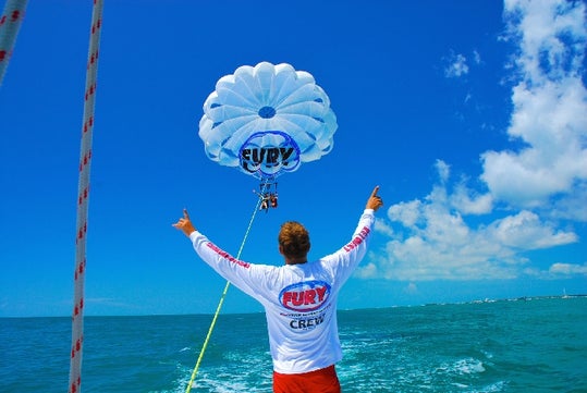 Man waving to the passengers in the chute on the Fury Water Adventure Parasailing in Key West, Florida.