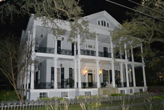 Iconic Garden District mansion framed by towering oaks.