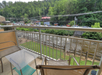 A balcony with two chairs and a glass table, overlooking a river.