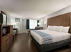 A guest room with a a King bed, sleeper sofa, and TV on a dresser.