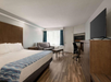 One King bed,  sleeper sofa, an electric fireplace, work area and a flat-screen TV inside a guest room.