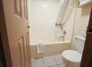 A small bathroom with a bathtub and shower curtain, a towel on the tub edge, and a toilet positioned near the door.