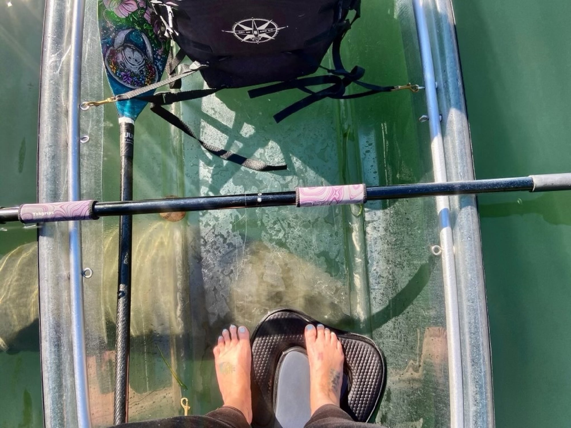 Clear kayak deck above shallow green water