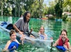 Kayakers and swimmers gathered around a clear kayak in a freshwater spring