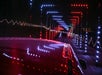 A car drives through a tunnel decorated with colorful LED lights forming geometric patterns.