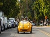 Tourists having fun while driving a bright yellow GoCar on a sunny day with another GoCar behind them on the GoCar Downtown and Balboa Park Tour.