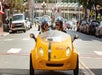 A man and woman wearing black helmets driving a yellow GoCar on the GoCar San Diego Harbor and Gaslamp Quarter Tour.