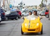 A man and woman wearing sunglasses and black helmets while driving a yellow GoCar and looking at the sights on the GoCar San Diego Harbor and Gaslamp Quarter Tour.
