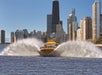 A yellow speedboat on the water with a city skyline in the background during a Lakefront Speedboat Tour in Chicago.
