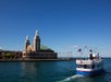 A passenger boat sails near Navy Pier in Chicago on a clear day, with the pier’s iconic building and flags visible in the background.