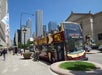 A double-decker bus on the street, with the words "BIGBUS CHICAGO" and "Hop on - Hop off" on its side in an outdoor scene, with a land vehicle, sky, road, and city in the background.