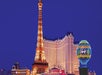 The illuminated replica Eiffel Tower and Paris balloon at Paris Las Vegas hotel are shown against a clear night sky.