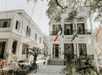 Outside of the two-storey Edgar Degas House with a flag on the porch and a balcony featuring outdoor elements such as plants, trees, and stairs.