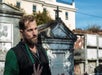A tour guide standing outdoors during a guided tour with tombs in the background, during the French Quarter Phantoms - St. Louis Cemetery Tour.