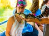 A girl holding a lizard, taken at the Cajun Pride Swamp Tours. The girl is wearing sunglasses and is outdoors.