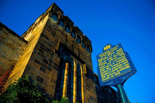 Outside view of the Eastern State Penitentiary in Philadelphia, Pennsylvania with a signage that provides information about the prison's design and its significance as a model for over 300 prisons worldwide.