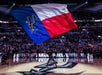A person holding a red, blue, and white Spurs flag amidst a large crowd of spectators at the San Antonio Spurs event with Go San Antonio Explorer Pass.