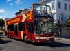 Double decker red bus by Big Bus San Francisco with several people aboard touring around Haight-Ashbury district in San Francisco with Go San Francisco Explorer Pass.