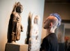 A visitor looking at a figure at Asian Art Museum with Go San Francisco Explorer Pass.
