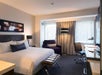 One king bed with plush bedding, flat-screen TV, work desk, and a small sofa inside a non-smoking guest room.